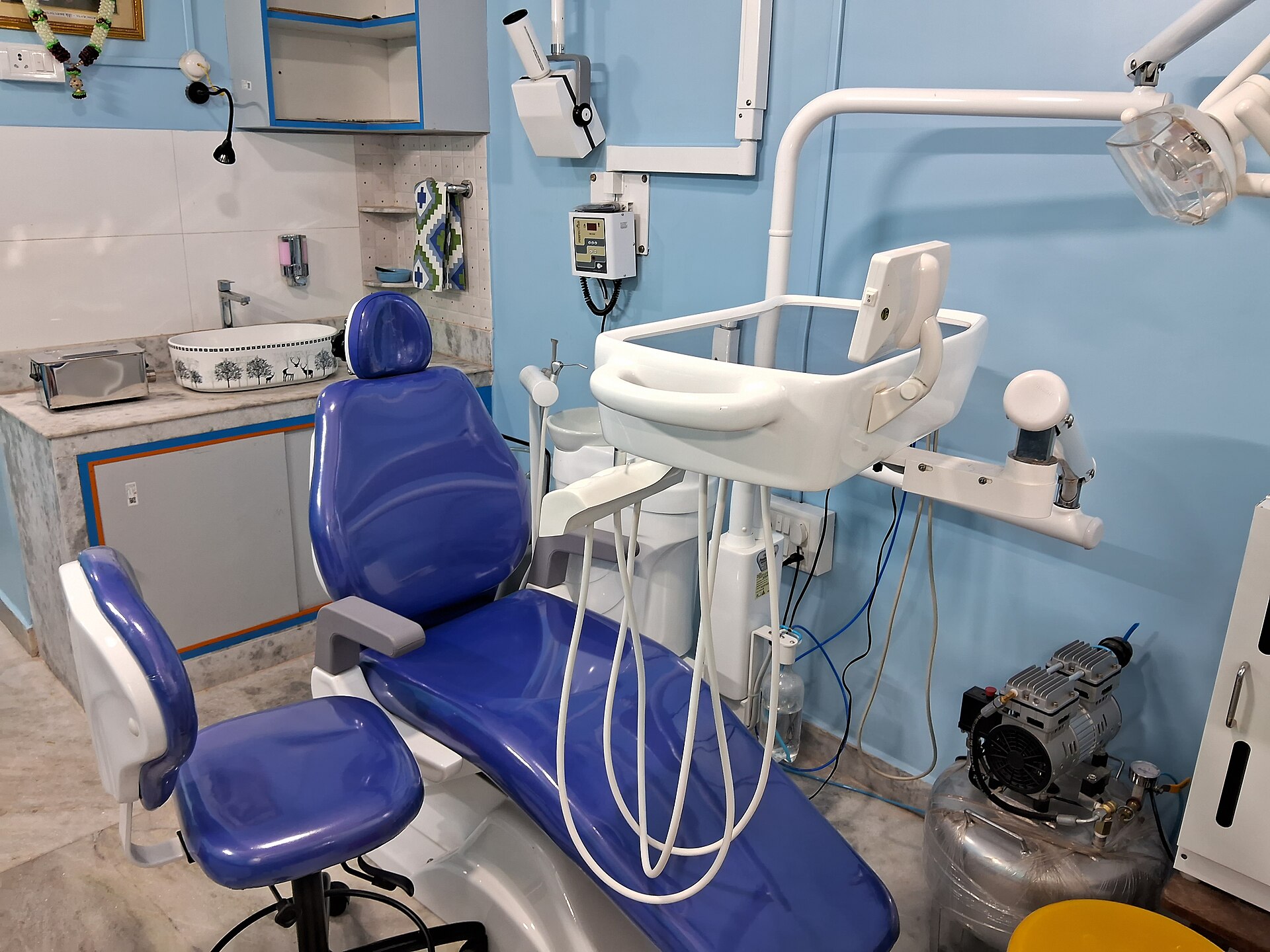 Niebieski fotel dentystyczny z lampą i stolikiem z narzędziami